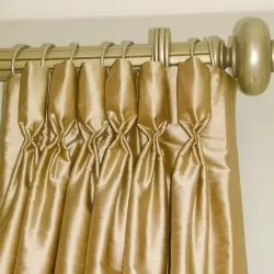 A gold-colored Goblet Pleat Curtain gracefully hangs on a rod