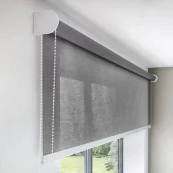 A window with a grey roller blind covering it, providing privacy and controlling the amount of sunlight entering the room