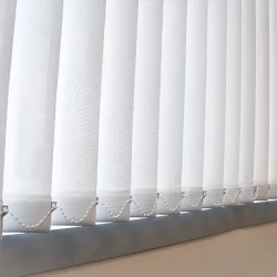 A close-up of a window with white vertical blinds, providing privacy and diffusing sunlight