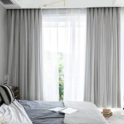 A cozy bedroom with a comfortable bed, blackout curtains, and a window offering natural light